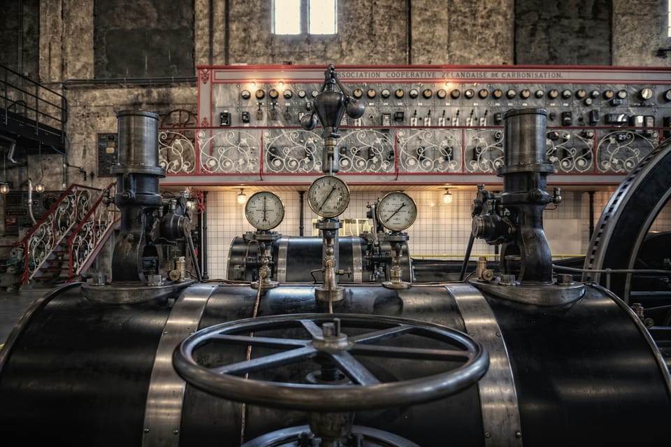 Elaborate vintage industrial control room with gauges, wheels, and an ornate red control panel
