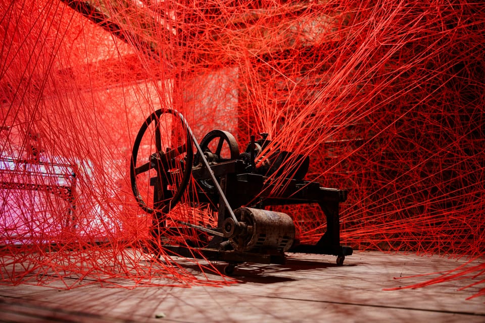An old machine wrapped in a dense web of red thread
